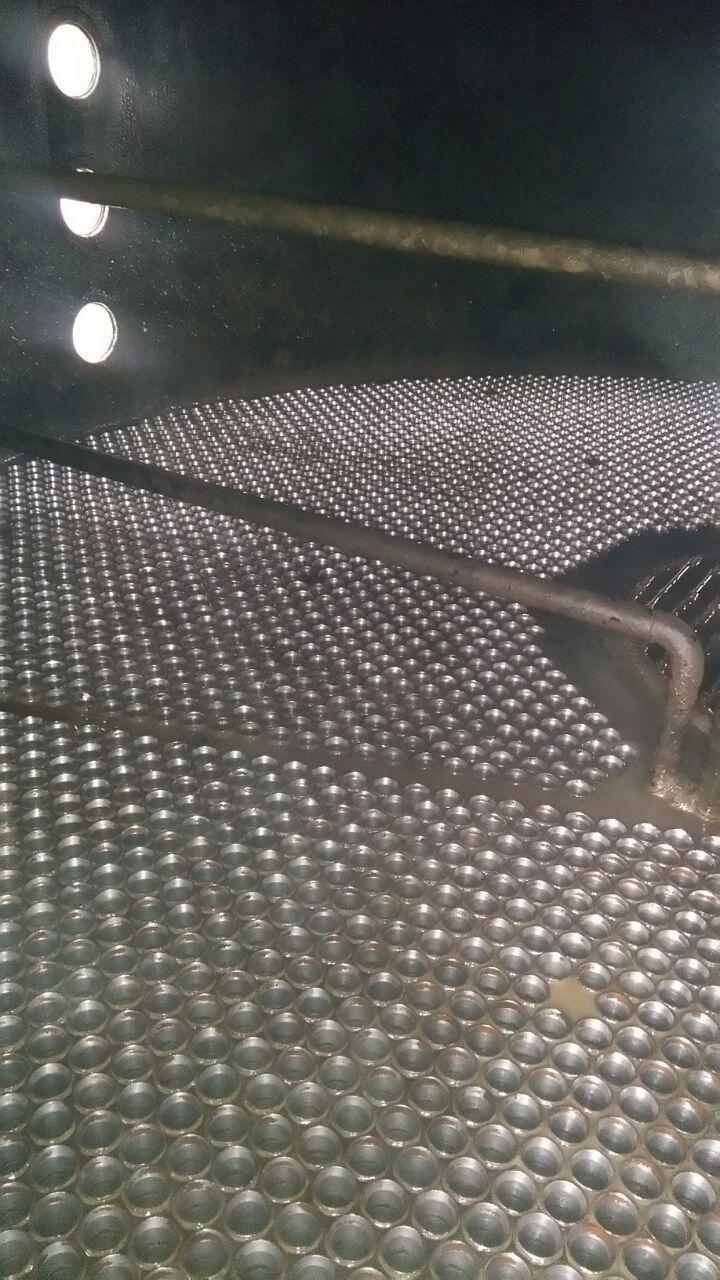 Interior de um evaporador com piso perfurado e tubulações, antes do processo de limpeza.