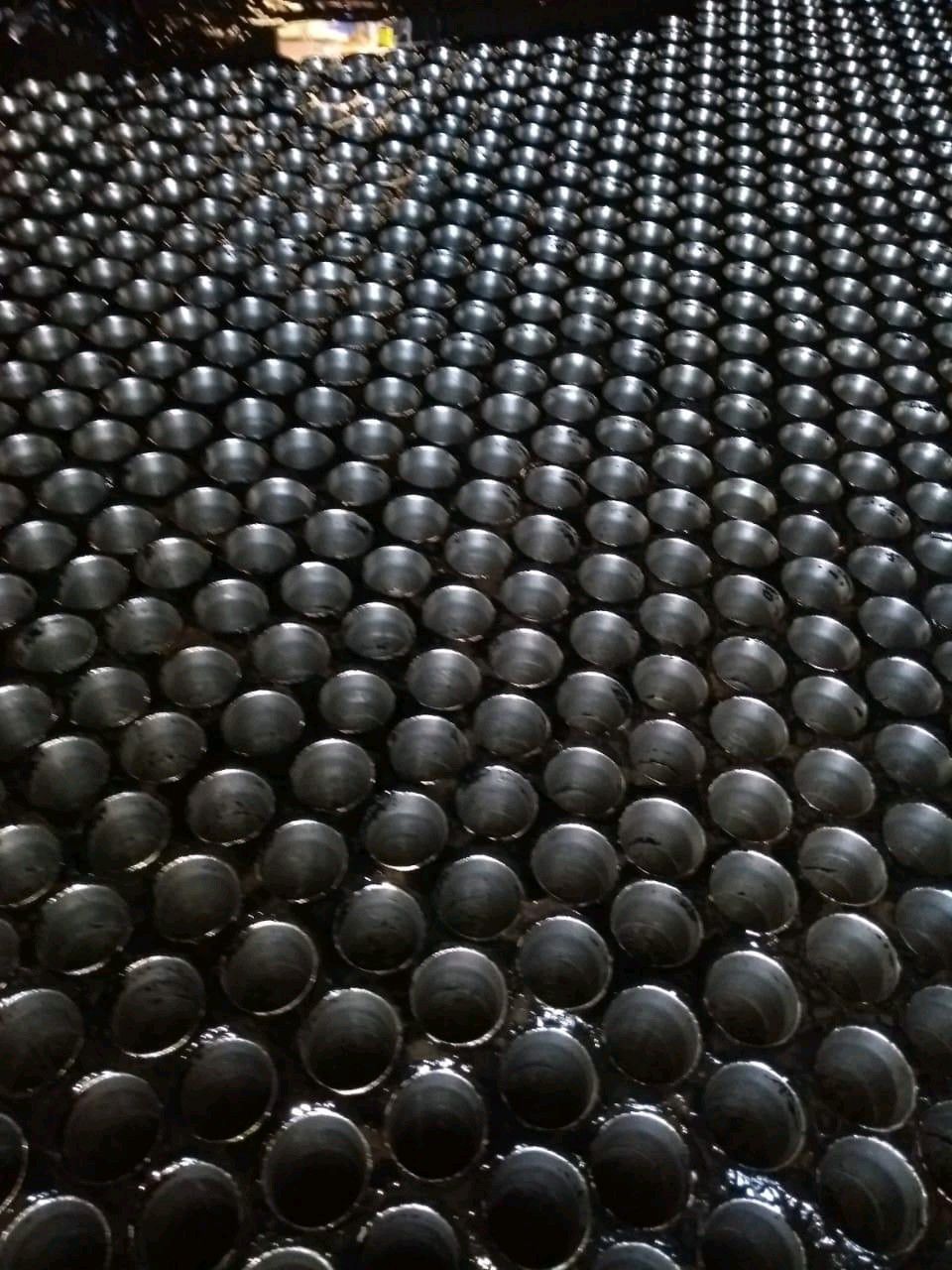 Piso perfurado de equipamento industrial com acúmulo de sujeira e resíduos escuros, precisando de higienização.