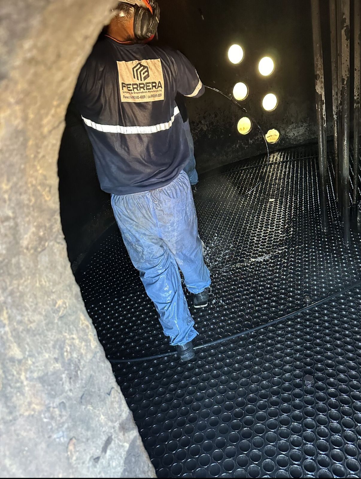 Profissional realizando limpeza interna de evaporador com jato de água de alta pressão.