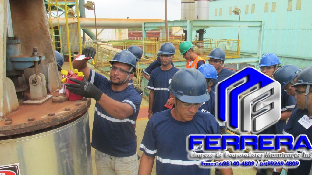 Equipe de técnicos da Ferrera com capacetes e óculos de proteção realizando manutenção em equipamento industrial.
